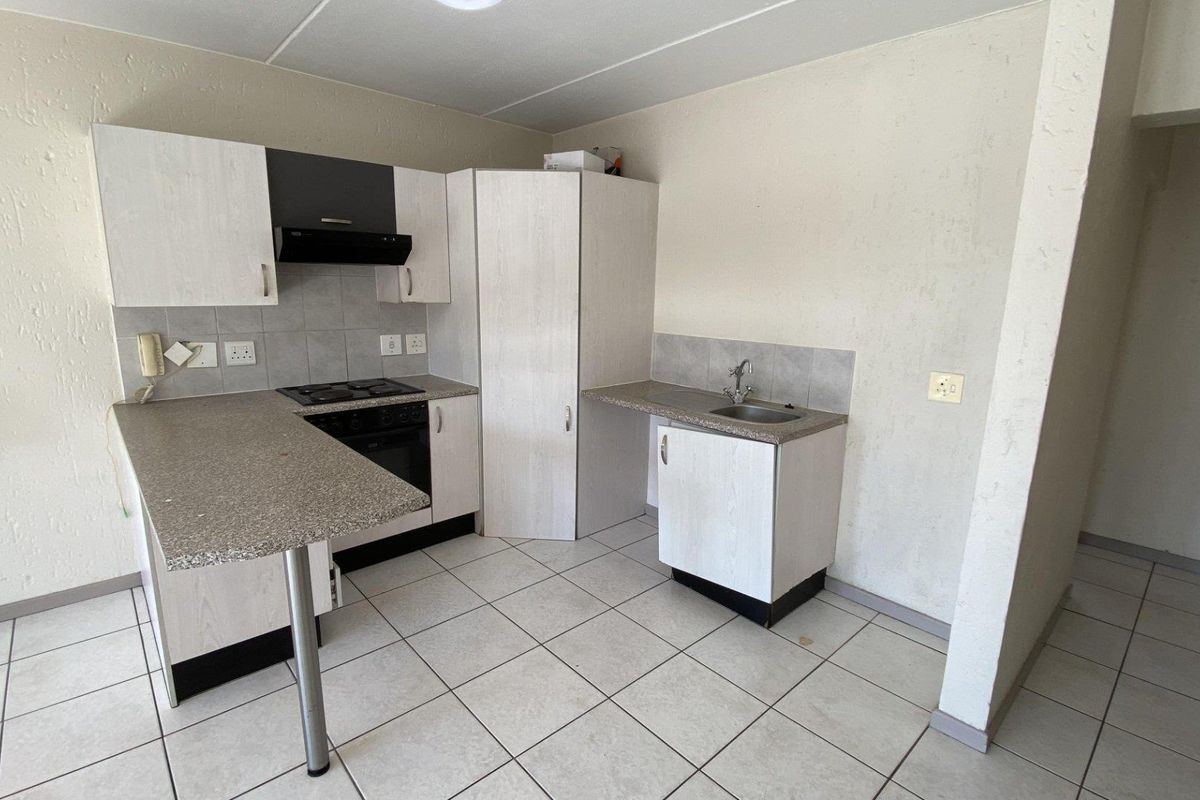 A functional kitchen featuring built-in cabinetry, a hob, oven, extractor fan, and tiled flooring, offering a clean and practical layout.
