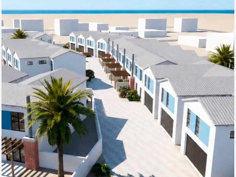 An aerial view of a modern townhouse development featuring uniform architectural design, paved driveways, and integrated garage access near the coast.