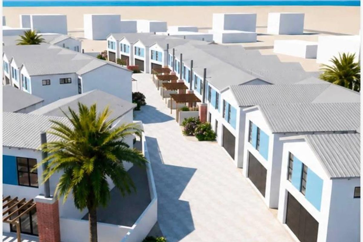 An aerial view of a modern townhouse development featuring uniform architectural design, paved driveways, and integrated garage access near the coast.