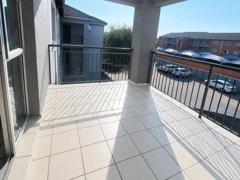 A spacious covered balcony featuring neutral floor tiles and a secure metal balustrade, offering an open outdoor area for relaxation.
