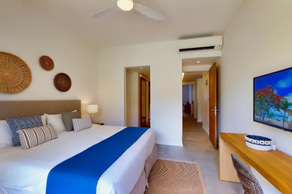 A well-maintained bedroom featuring a ceiling fan, wall-mounted air conditioning unit, and tiled flooring, providing a comfortable and functional living space.