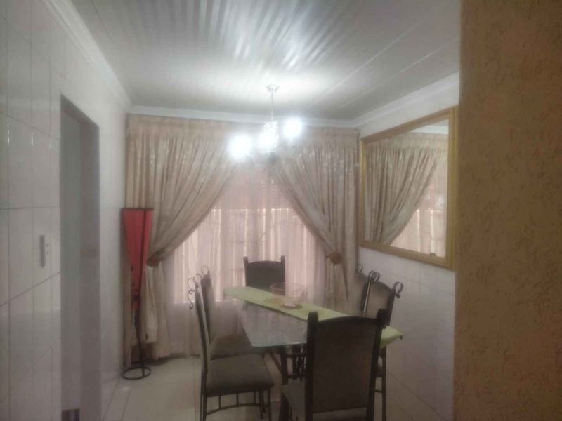 A dining room featuring tiled flooring, coved ceiling details, and a large wall-mounted mirror, providing a functional space for family meals.