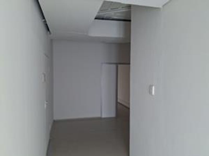 An empty, neutral-toned office space featuring a recessed ceiling design and an internal doorway, currently in need of finishing touches.