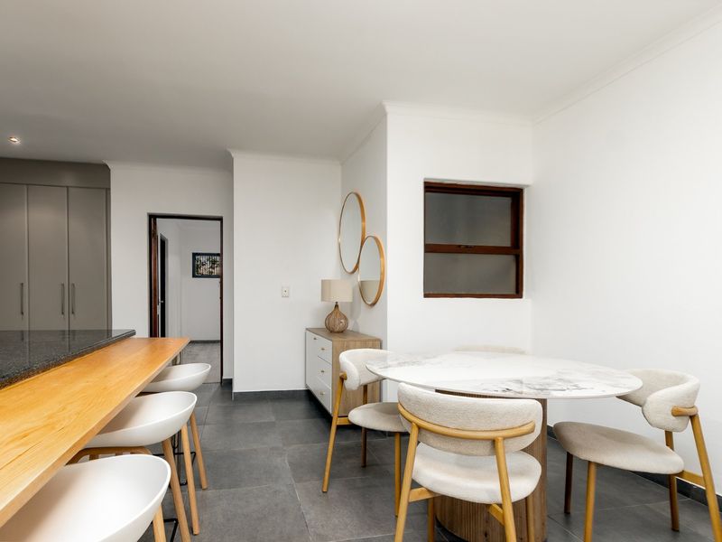 Open plan living area featuring a granite kitchen island with timber breakfast bar, tiled flooring, and neutral finishes throughout.