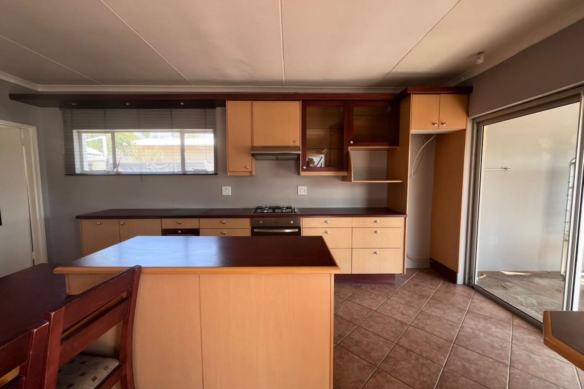 Functional kitchen featuring light wood cabinetry, dark laminate countertops, built-in oven and gas hob, tiled flooring, and direct access to the outdoor area.