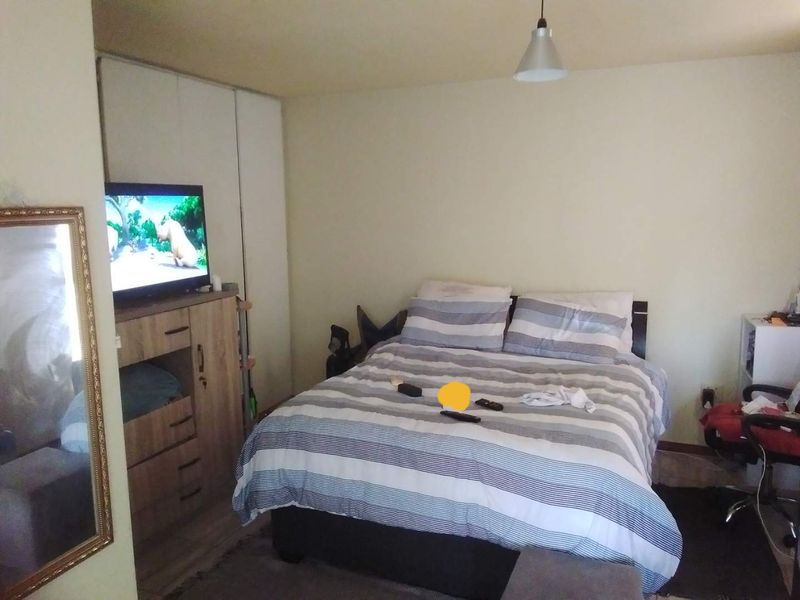 A functional bedroom featuring a built-in wardrobe and neutral wall finishes, providing a comfortable space for rest.