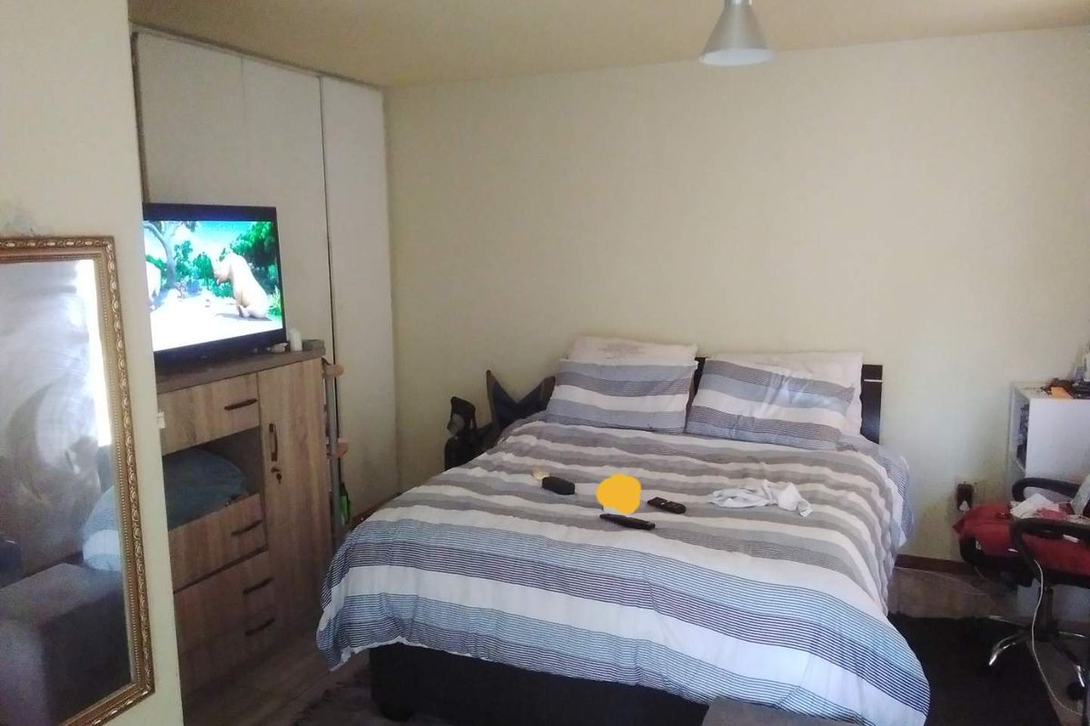 A functional bedroom featuring a built-in wardrobe and neutral wall finishes, providing a comfortable space for rest.