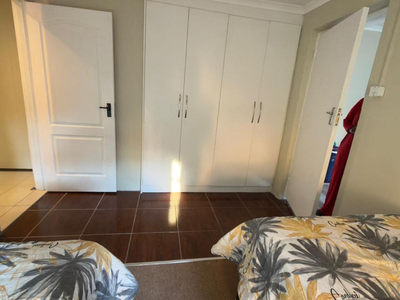 A bedroom featuring built-in cupboards, tiled flooring, and access to adjacent rooms via internal doors.
