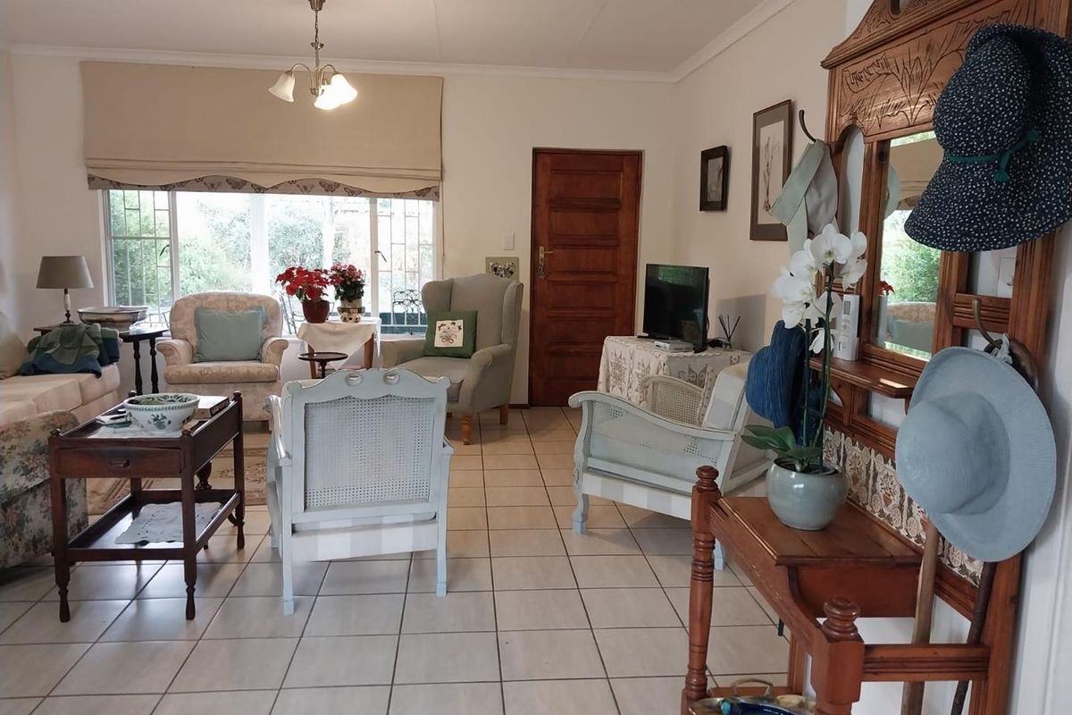 A spacious living room featuring tiled flooring, large windows with blinds, and a solid wood door, offering a comfortable and functional living space.