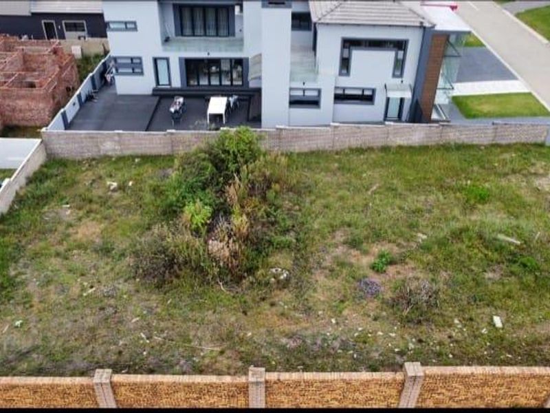 Aerial view of a vacant residential plot featuring perimeter brick walling and natural vegetation, situated within a developed estate.