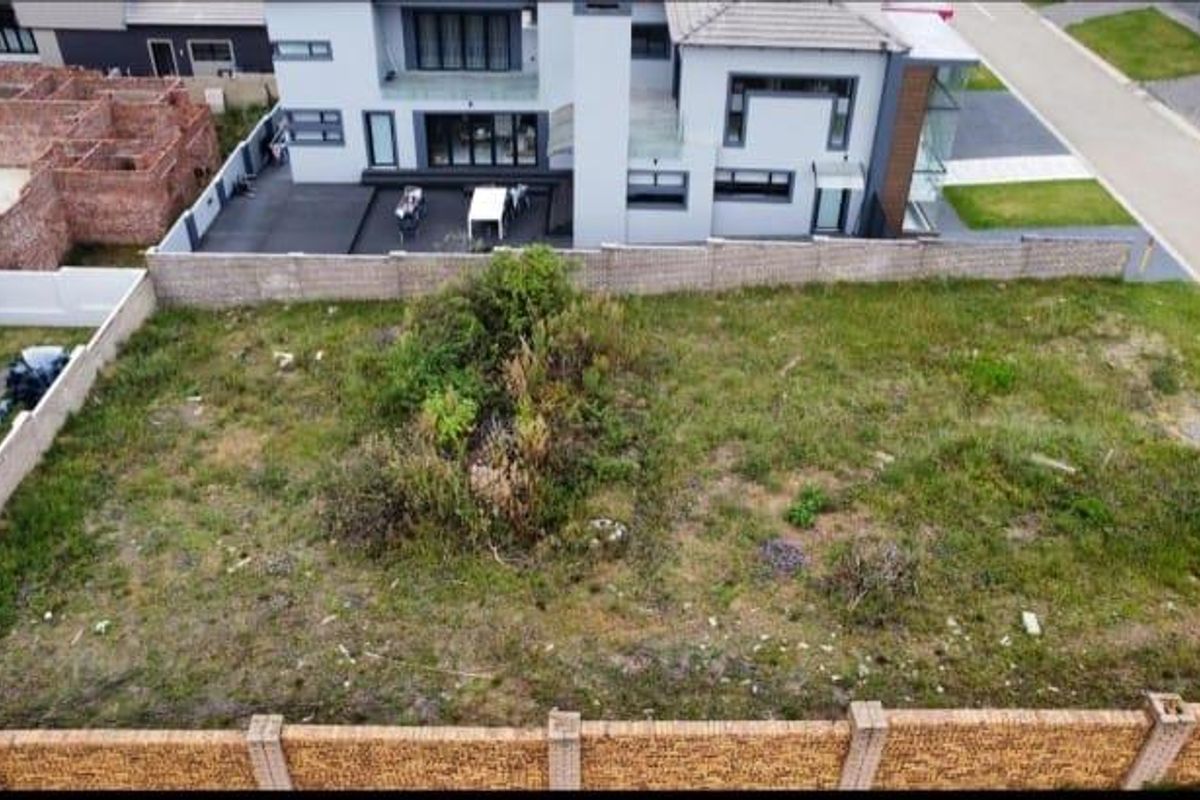 Aerial view of a vacant residential plot featuring perimeter brick walling and natural vegetation, situated within a developed estate.