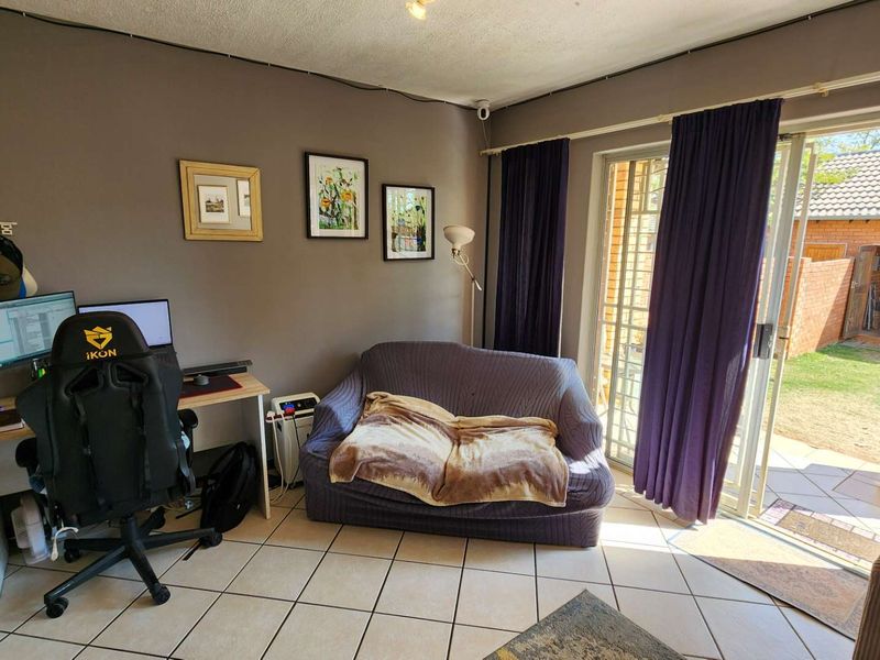 Living room area featuring tiled flooring and a sliding glass door providing direct access to the rear garden and patio space.