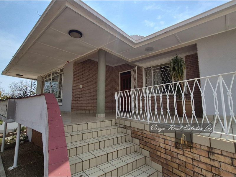 Front entrance featuring a covered porch, tiled staircase, and brick facade with security features.