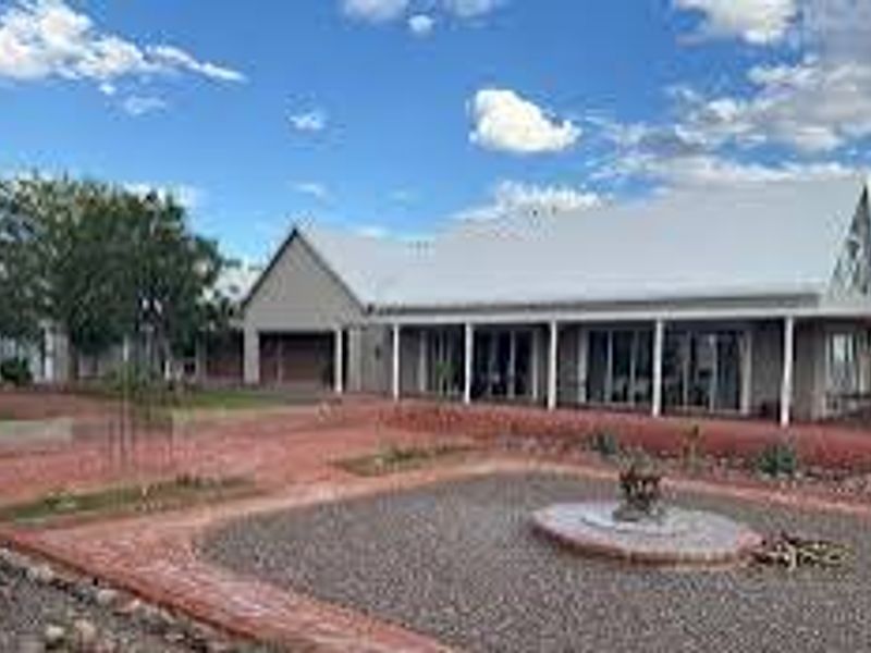 Rear view of the farm residence featuring a spacious covered patio, extensive brick paving, and a landscaped gravel garden area.