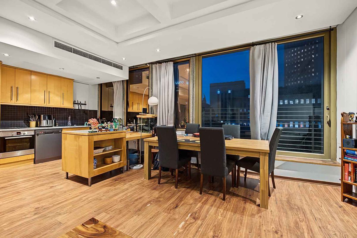Spacious open-plan kitchen and dining area featuring modern timber cabinetry, integrated appliances, recessed lighting, and large glass doors leading to an outdoor balcony.