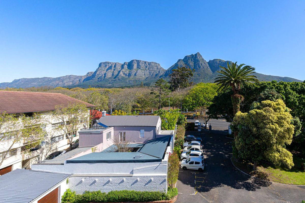 Aerial view of the apartment complex grounds featuring paved parking areas, established landscaping, and scenic mountain views in the background.