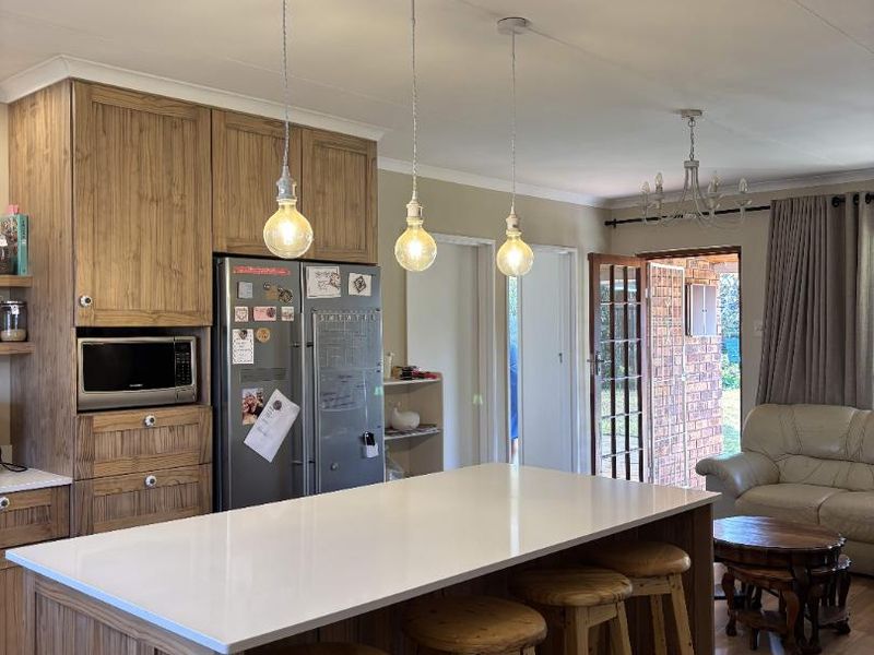 Open plan kitchen featuring a central island with quartz countertop, timber cabinetry, built-in microwave, and direct access to the outdoor area.