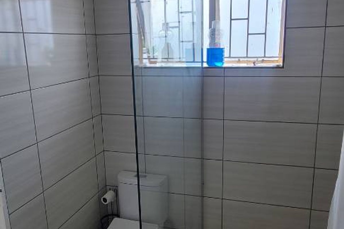 A modern bathroom featuring a walk-in shower with a glass partition, tiled walls, and a standard toilet.