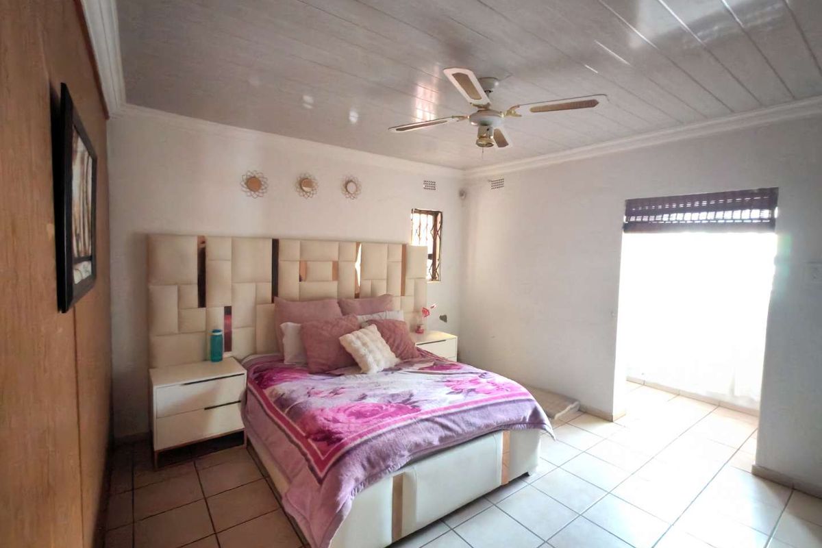 A bedroom featuring tiled flooring, a ceiling fan, and timber-look ceiling panels, with access to an outdoor area through a security gate.
