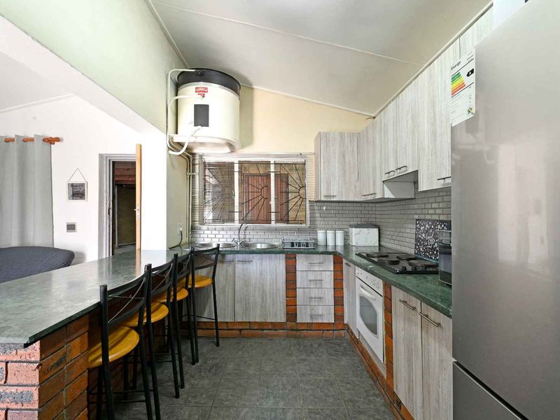 Functional kitchen featuring brick-based cabinetry, laminate countertops, subway tile backsplash, and an integrated electric hob and oven.