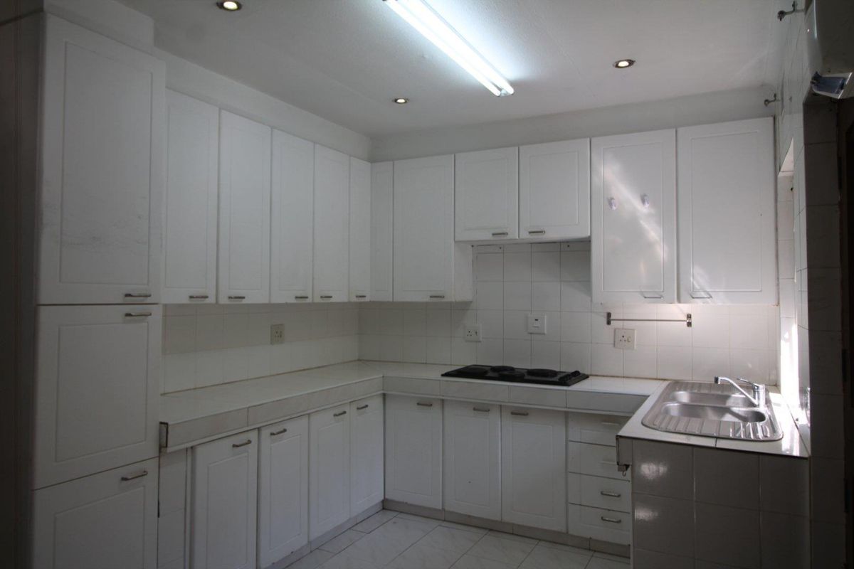A functional kitchen featuring white cabinetry, tiled countertops, a built-in hob, and a double-basin stainless steel sink.