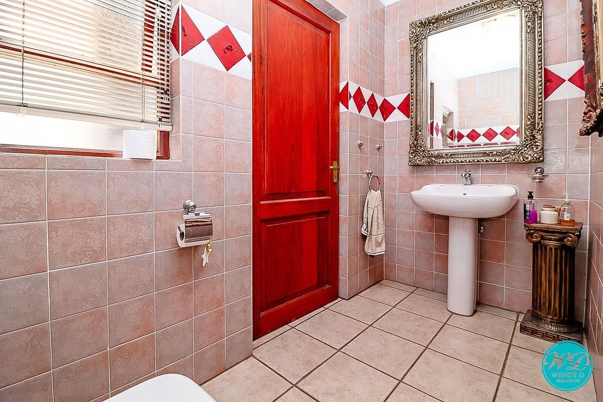 A functional bathroom featuring a pedestal basin, tiled walls with decorative accents, and a solid wood door.