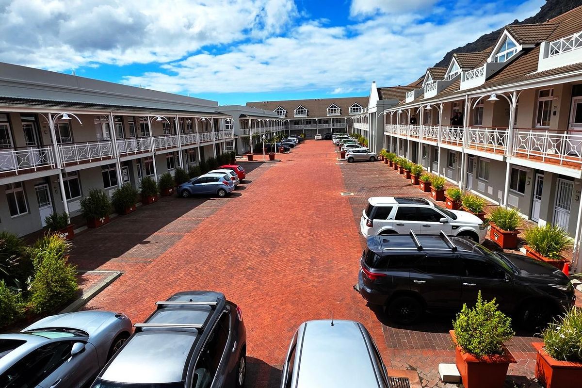 An elevated view of a commercial office complex courtyard featuring paved brick walkways, landscaped planters, and covered walkways along the building facades.