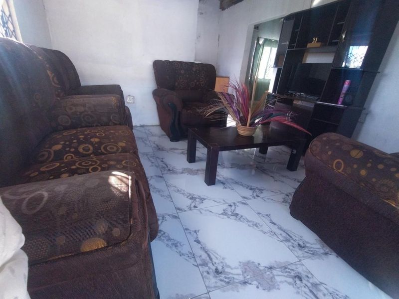 A living room featuring marble-look ceramic floor tiles and visible wall imperfections, offering potential for cosmetic updates to enhance the space.