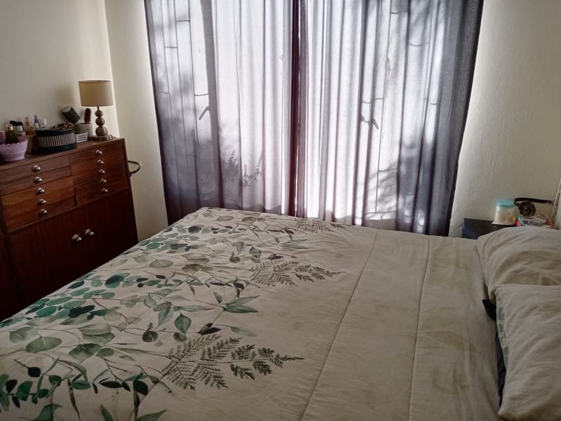 A standard bedroom featuring a large window with installed curtain tracks, providing natural light to the space.