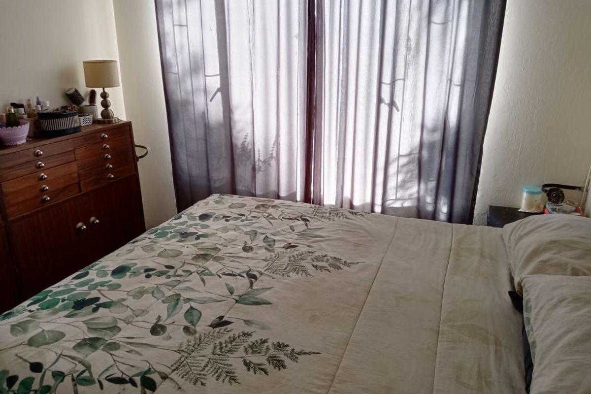 A standard bedroom featuring a large window with installed curtain tracks, providing natural light to the space.