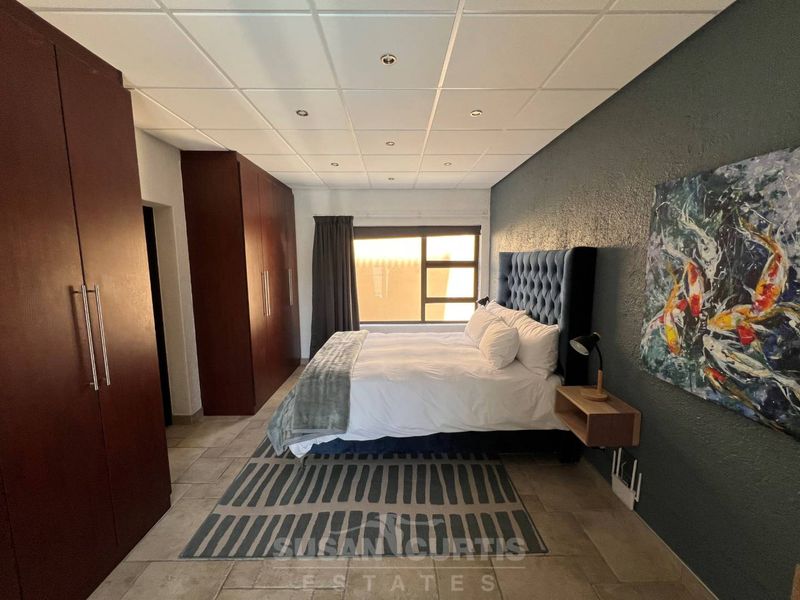 Spacious bedroom featuring built-in cupboards, tiled flooring, and a modern drop ceiling with recessed lighting.