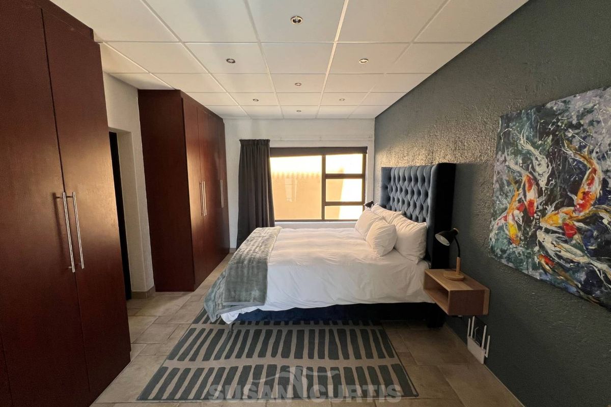 Spacious bedroom featuring built-in cupboards, tiled flooring, and a modern drop ceiling with recessed lighting.