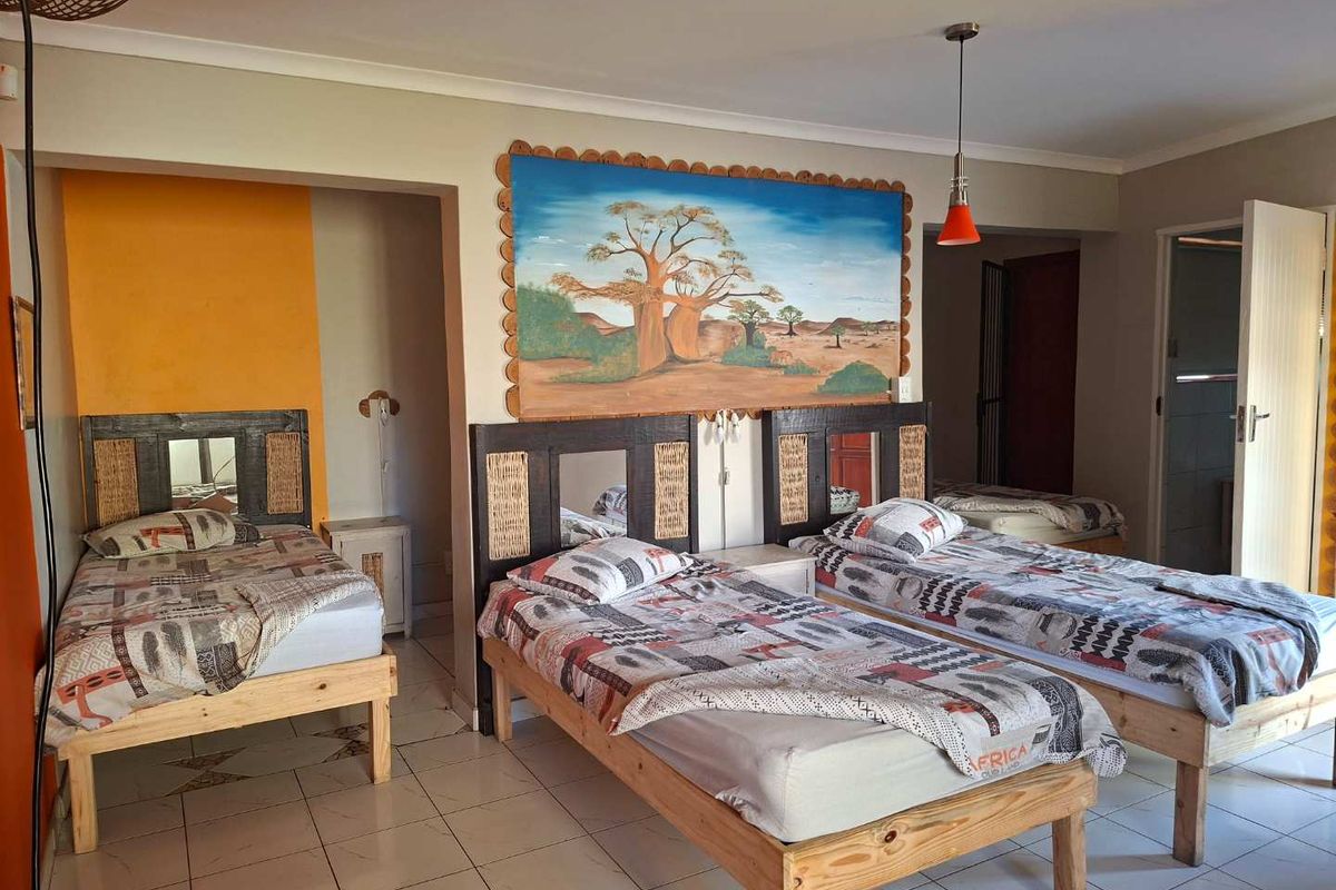 Spacious bedroom featuring tiled flooring, neutral wall finishes, and a built-in alcove area, offering a functional layout for multiple beds.