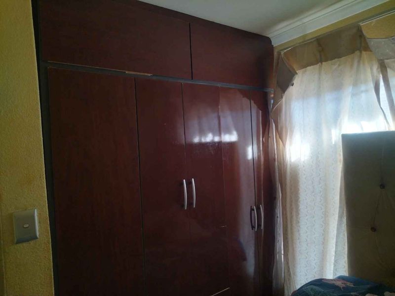 A bedroom featuring dark wood built-in cupboards with overhead storage and decorative ceiling cornice.