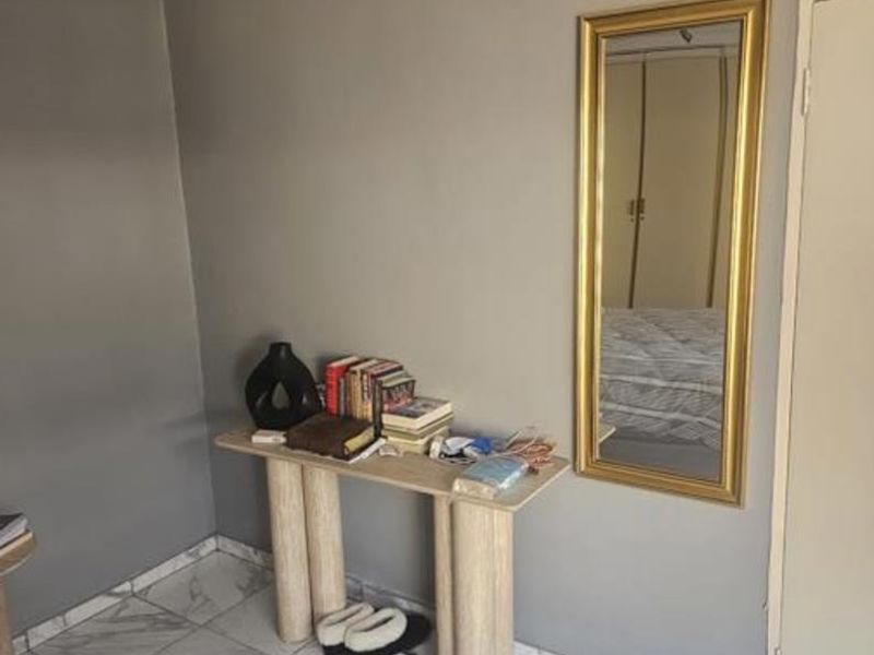 A bedroom featuring marble-look tiled flooring, neutral grey walls, and a built-in cupboard, offering a clean and functional living space.