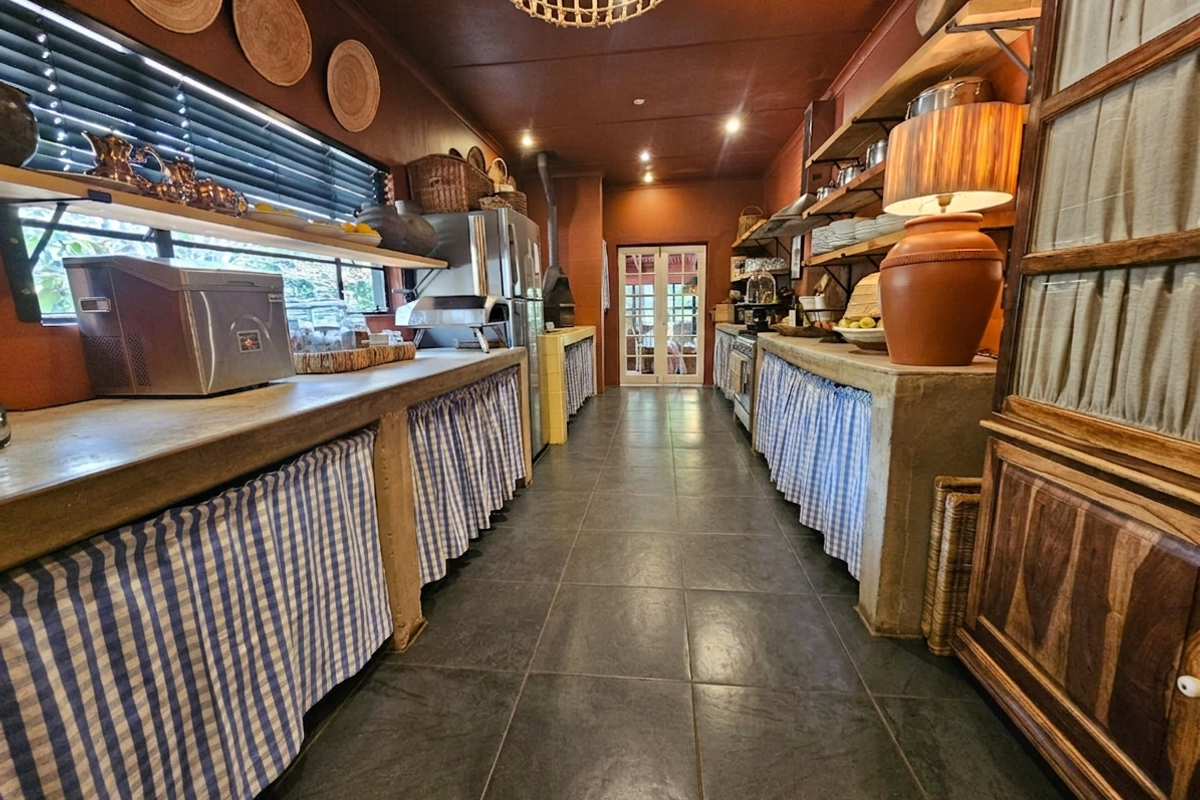 A rustic-style kitchen featuring concrete countertops, open shelving, tiled flooring, and a built-in pizza oven, offering a unique and functional culinary space.