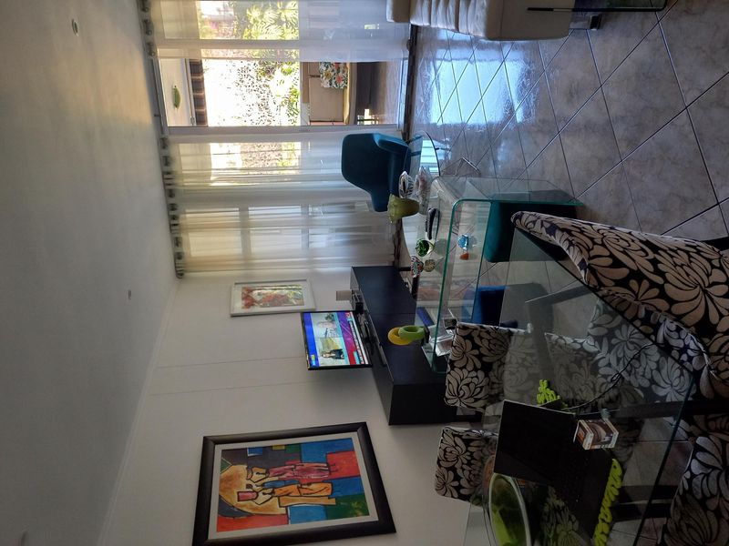 A bright living room featuring tiled flooring and a large sliding glass door providing access to an outdoor patio area.