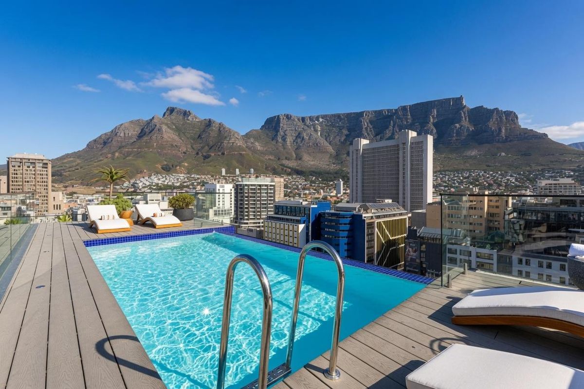 Rooftop infinity pool featuring a glass balustrade and composite decking, offering panoramic views of Table Mountain and the city skyline.