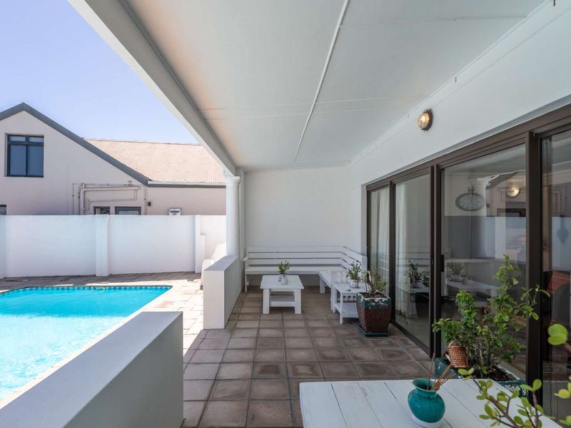A covered patio area featuring tiled flooring and sliding glass doors, providing direct access to the swimming pool and outdoor space.
