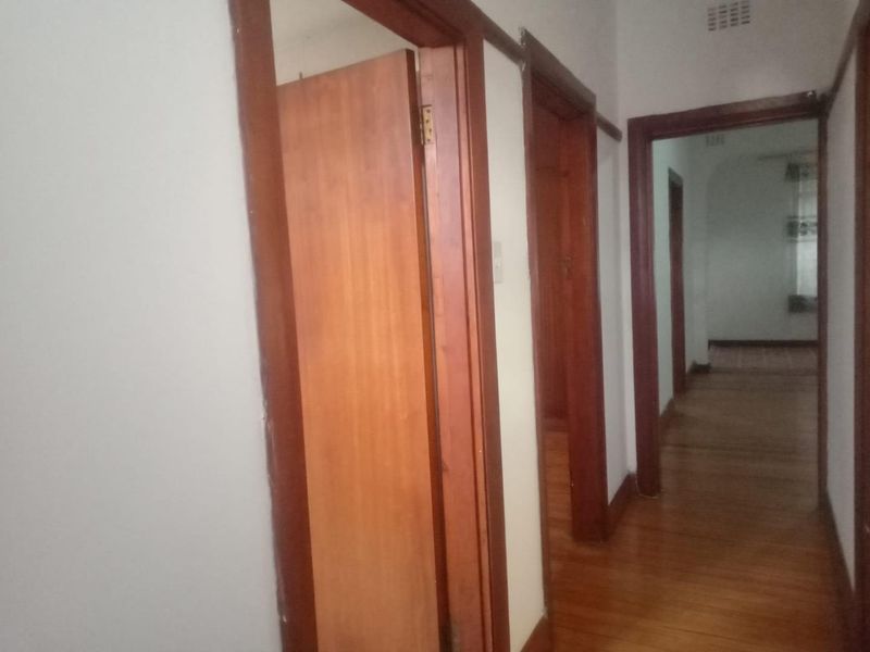 A narrow interior hallway featuring traditional timber door frames, wooden doors, and original timber flooring throughout the apartment corridor.