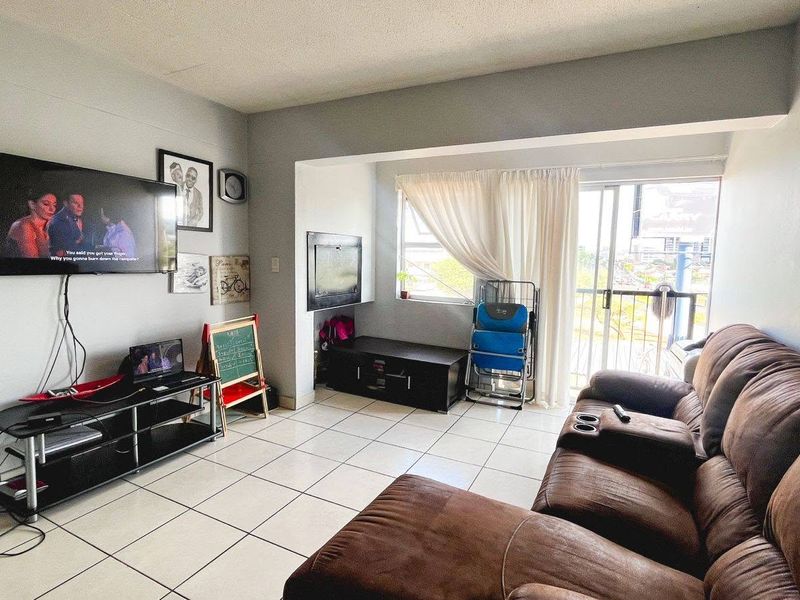 A functional living room featuring tiled flooring and a sliding glass door providing access to an outdoor balcony area.