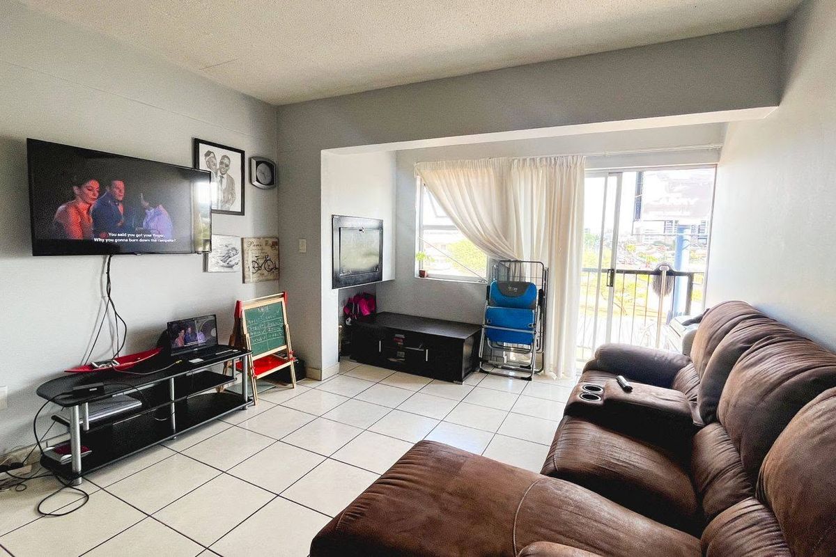 A functional living room featuring tiled flooring and a sliding glass door providing access to an outdoor balcony area.
