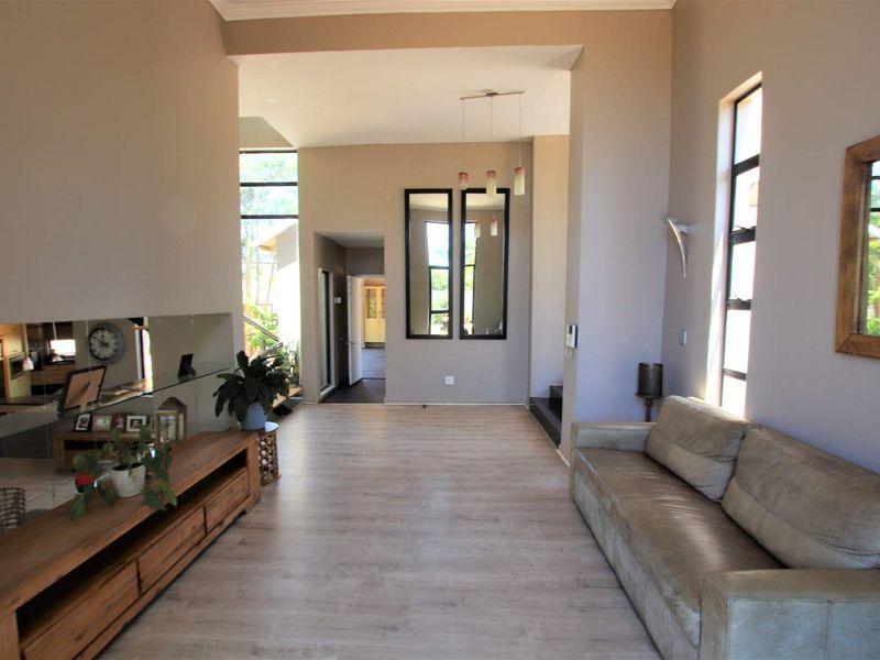 Spacious living area featuring light-toned laminate flooring, high ceilings, and large windows that provide ample natural light throughout the room.