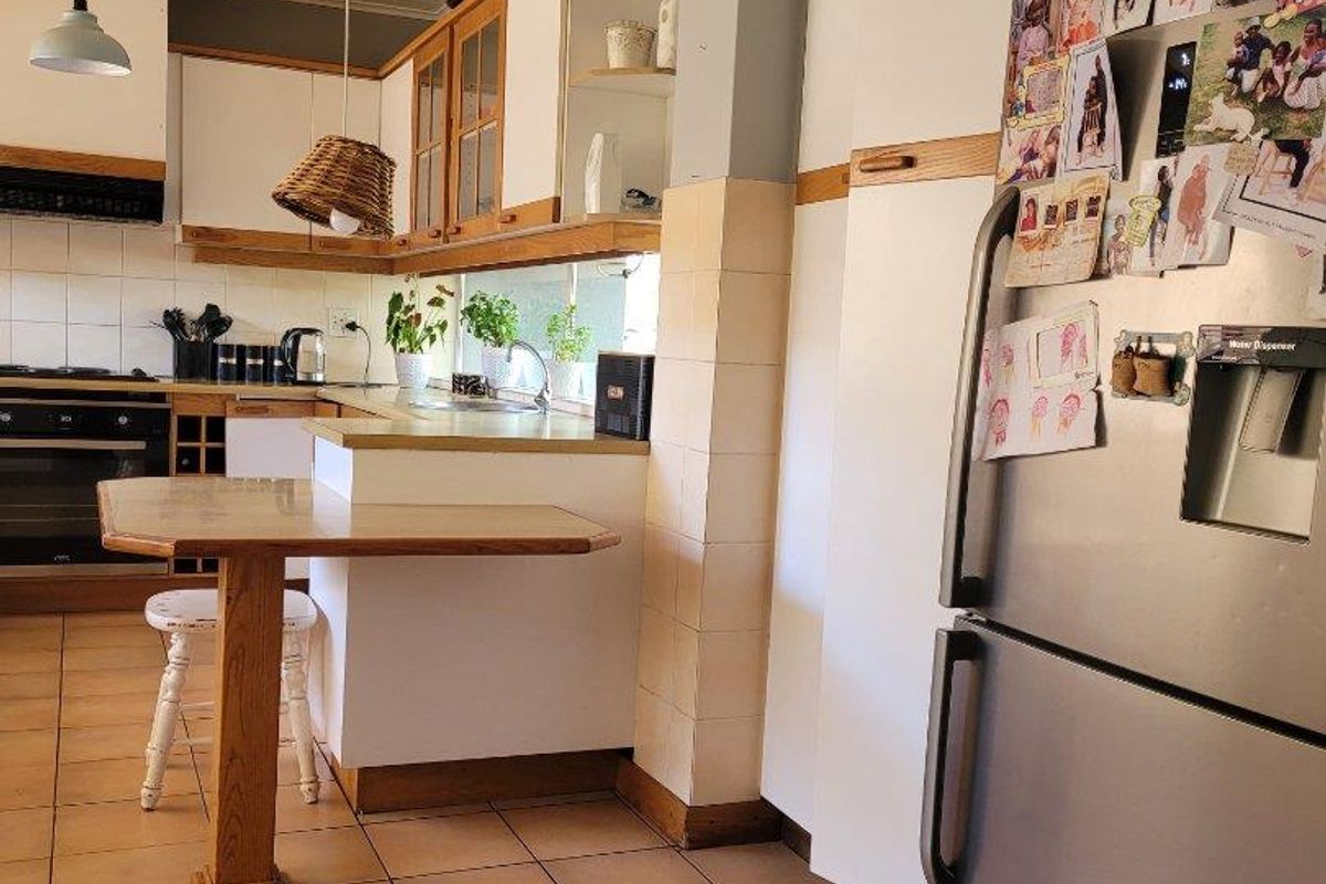 A functional kitchen featuring built-in cabinetry, a breakfast bar, tiled flooring, and integrated cooking appliances, offering a practical layout for daily use.