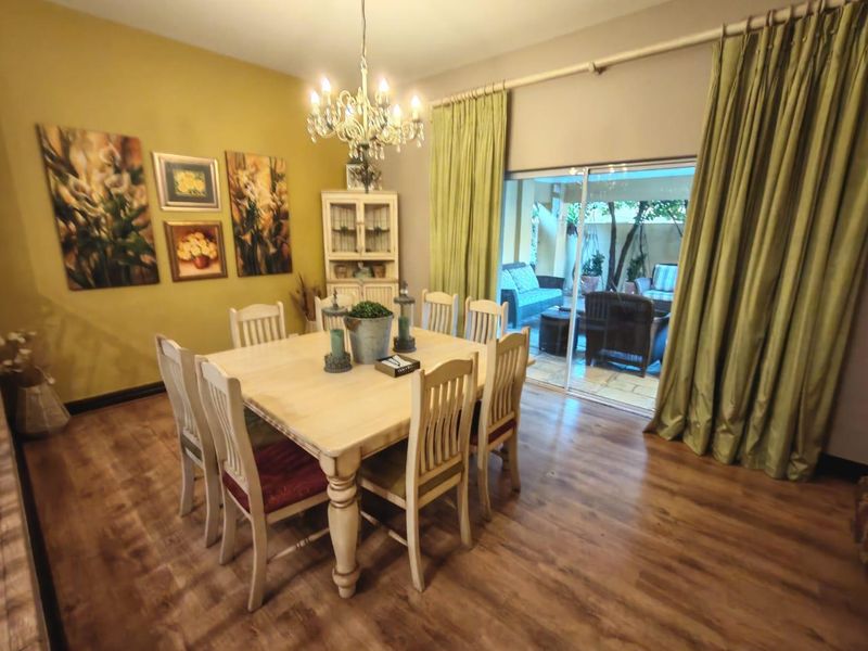 A dining room featuring laminate flooring, a central chandelier, and large sliding glass doors providing access to the outdoor patio area.