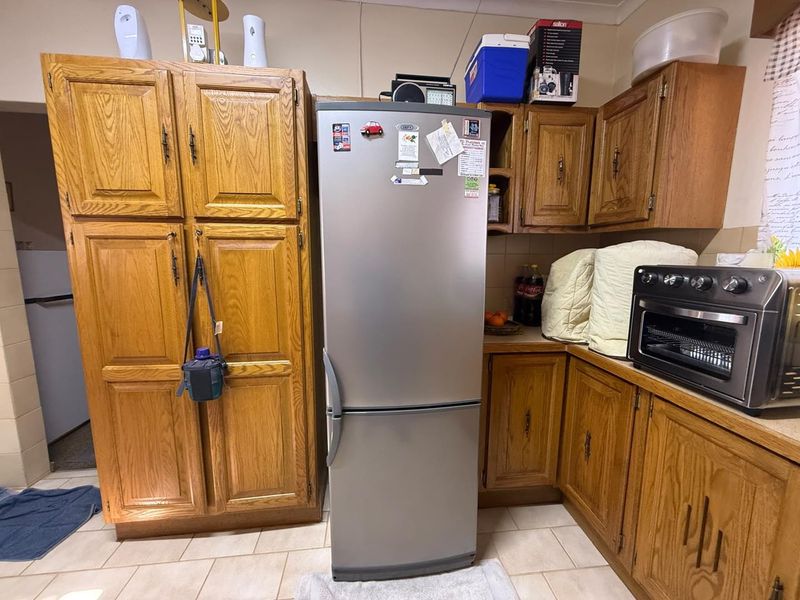 A functional kitchen featuring traditional oak cabinetry, tiled flooring, and ample storage space, offering a classic aesthetic ready for modern updates.
