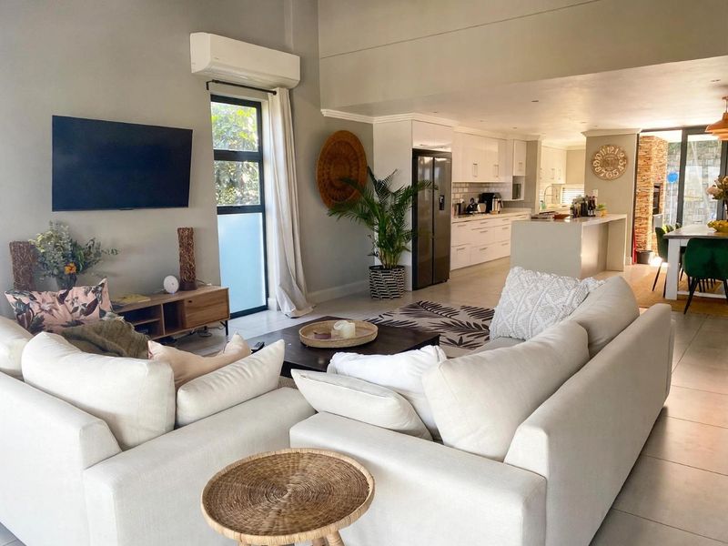 Spacious open-plan living area featuring a modern kitchen with island, tiled floors, and split-system air conditioning, seamlessly flowing into the lounge space.