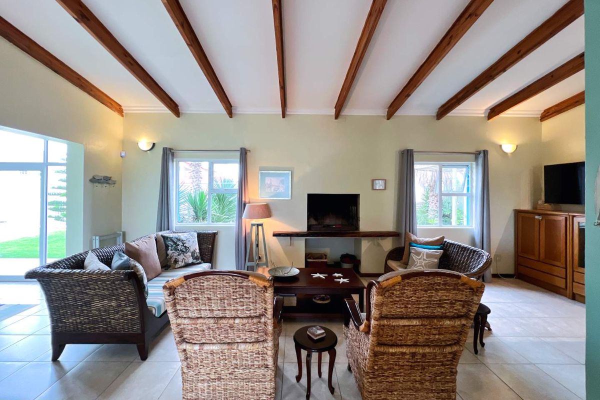 Spacious living room featuring exposed timber ceiling beams, tiled flooring, and a built-in fireplace, offering a comfortable and inviting atmosphere.
