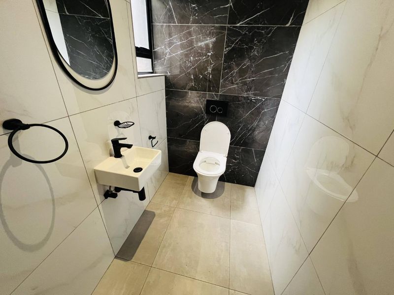 Modern guest bathroom featuring high-contrast black and white marble-look tiling, a wall-mounted toilet with concealed cistern, and a sleek wall-mounted basin.