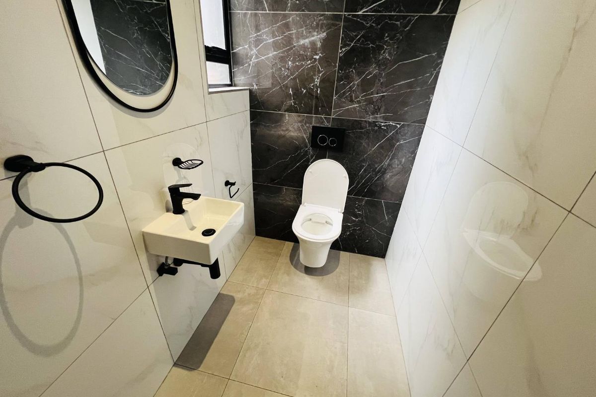 Modern guest bathroom featuring high-contrast black and white marble-look tiling, a wall-mounted toilet with concealed cistern, and a sleek wall-mounted basin.